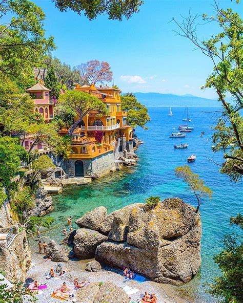 People Are Relaxing On The Beach In Front Of Some Houses And Boats Near