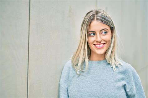 Jeune fille blonde souriante heureuse debout à la ville Photo Gratuite