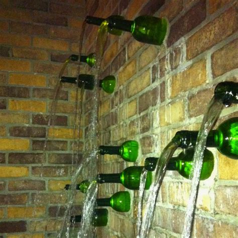 Several Green Wine Bottles Are Lined Up On The Wall With Water Coming