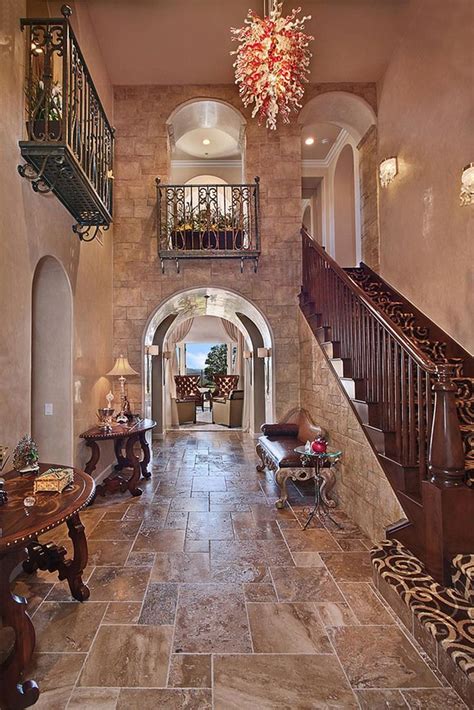 An Entry Way With Stairs Tables And Chandelier On The Second Floor