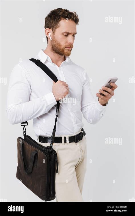 Image Of Focused Blonde Man Using Cellphone And Wireless Earphones