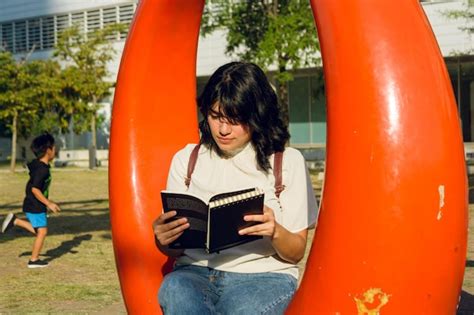 Joven Latina Sentada En Un Parque Concentrada Leyendo Un Libro Foto Premium