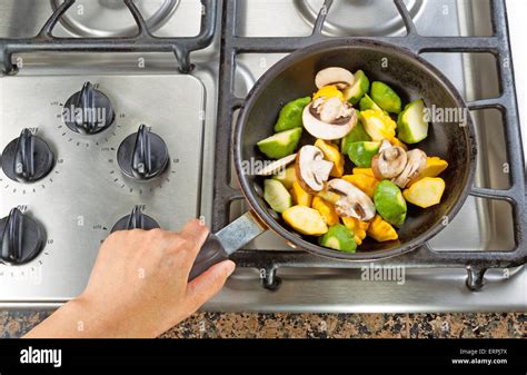 High Angle View Of Hand Holding Frying Pan While Cooking Vegetable In