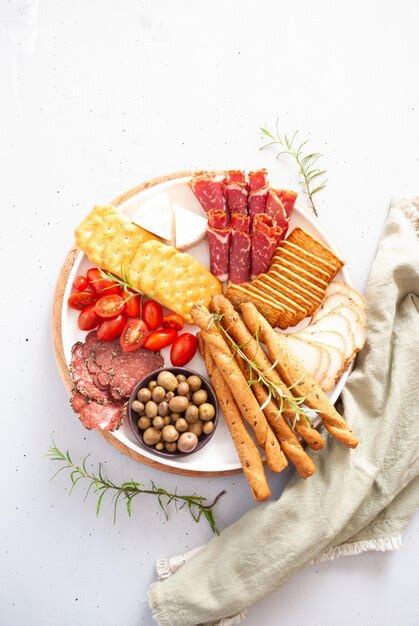 Un Plato De Carnes Quesos Y Aceitunas Con Una Aceituna Verde Foto