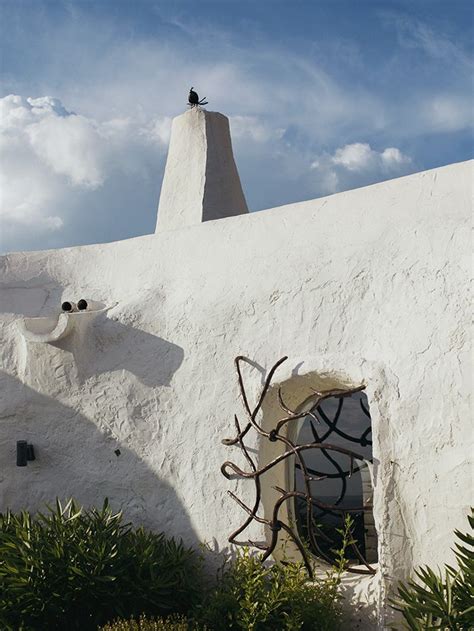 A White Stucco Building With An Iron Sculpture On The Front And