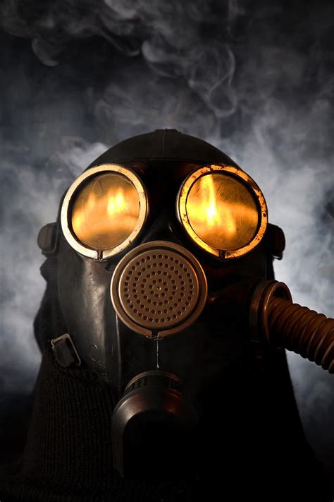 Man In Gas Mask With Fire Reflection In The Eyes Over Smoky Background