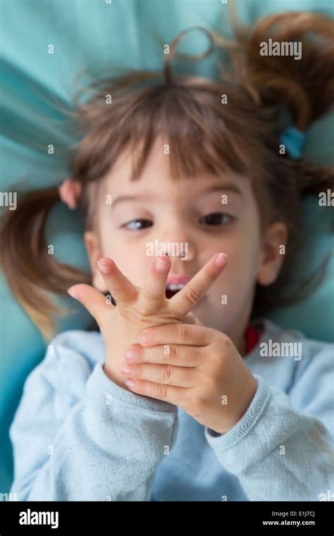 Portrait Of Little Girl Lying On Bean Bag Counting With Fingers