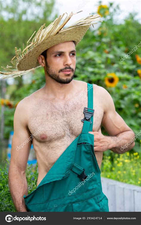 Handsome Gardener With Green Pants And Straw Hat Standing In Gar Stock