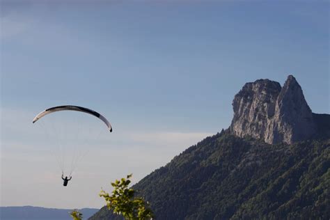 Faceless person flying paraglider over green countryside · Free Stock Photo