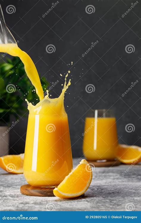 Orange Juice Pouring Into Glass With Splash On Table Stock Image