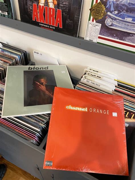 An Orange Vinyl Album Sitting On Top Of A Book Shelf Filled With Cds