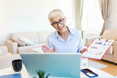 Mature Businesswoman Presenting Charts And Graphs On Video Call Online