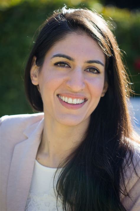 A Woman With Long Black Hair Smiling At The Camera While Wearing A