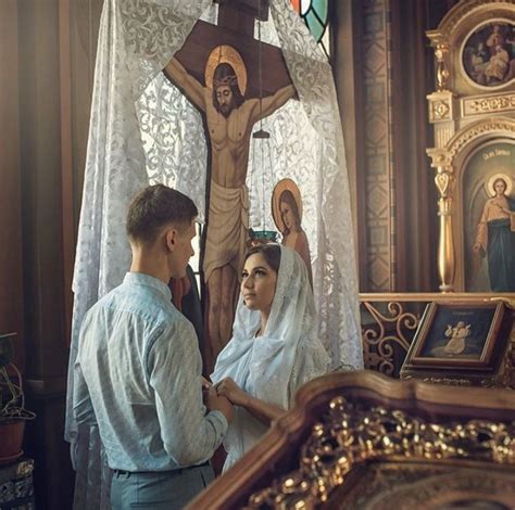 A Man And Woman Standing In Front Of A Crucifix