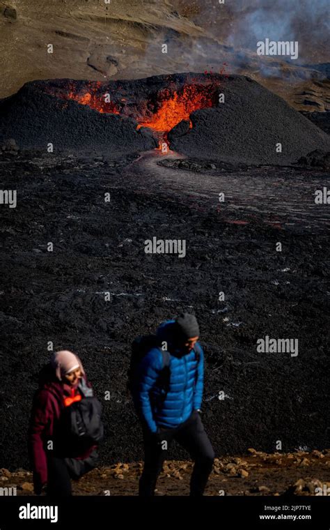 Tourists Visit A Heart Shaped Crater As Lava Flows From The Volcano In Fagradalsfjall Iceland