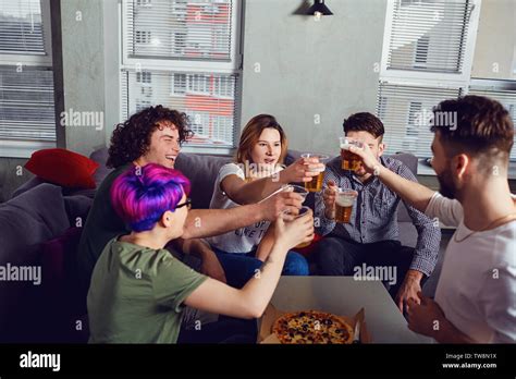 A Group Of Friends Is Clinking Glasses With Beer In The Room Stock