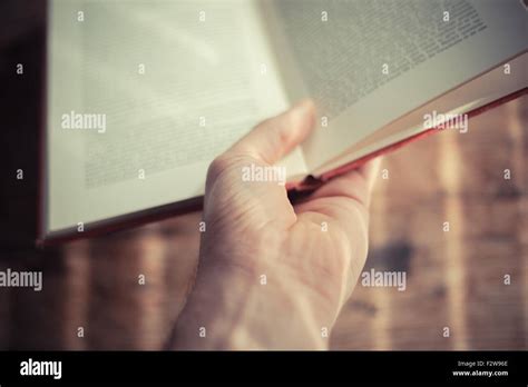 Hand Is Holding An Open Book At A Table Stock Photo Alamy