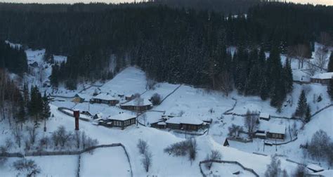 Aerial View Of Wooden Houses In A Village Between Two Hills In Winter