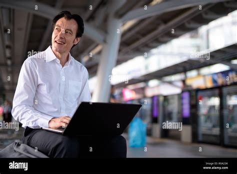 Mature Handsome Businessman Using Laptop Computer In Train Station