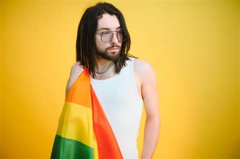 Hombre gay feliz divirtiéndose sosteniendo el símbolo de la bandera del arco iris de la