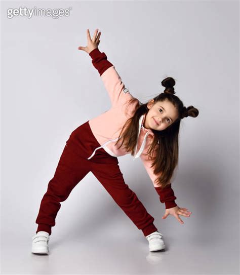 Cheerful Brunette Kid Girl In Stylish Pink Brown Sportswear Is Bending