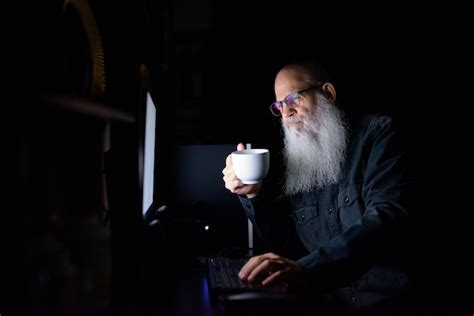Premium Photo Mature Bald Bearded Man Drinking Coffee While Working