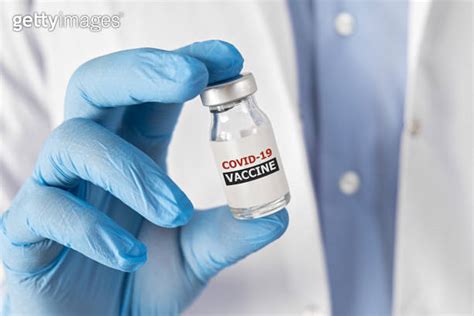 Doctor In White Robe And Gloves Hold Syringe In Hand With Liquid