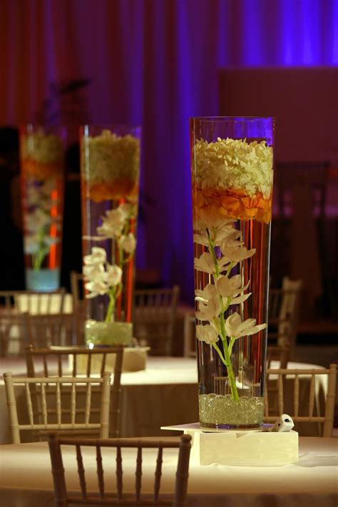 Cylinder Vases With Cymbidium Orchids And Floating Petals On Light