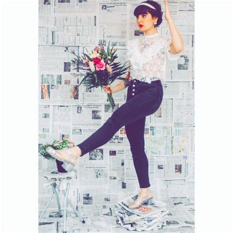 A Woman Standing On Top Of A Pile Of Newspapers With Flowers In Her