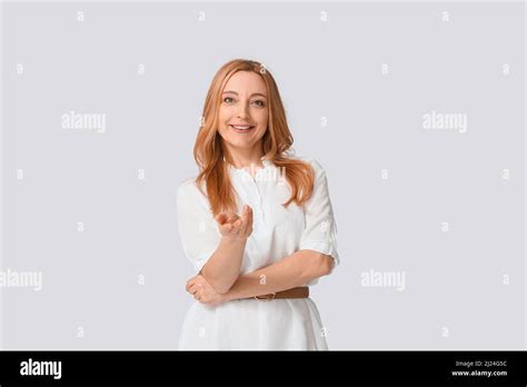 Mature Woman Showing Come Here Gesture On Grey Background Stock Photo