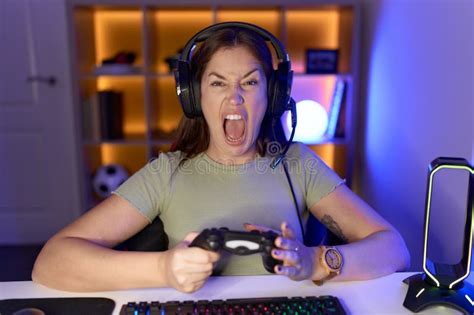 Beautiful Brunette Woman Playing Video Games Wearing Headphones Angry And Mad Screaming