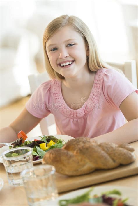 Muchacha Que Tiene Comida En La Mesa De Comedor Imagen De Archivo