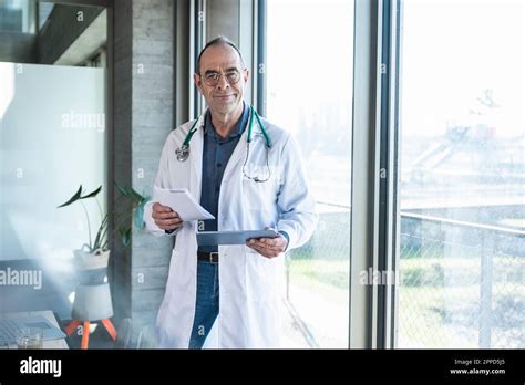 Smiling Mature Doctor Holding Prescription And Tablet PC Stock Photo