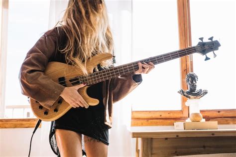 Jeune Femme Jouant De La Guitare électrique Près De La Fenêtre Photo