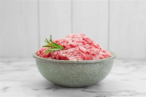 Bowl Of Raw Fresh Minced Meat With Rosemary On White Marble Table Stock