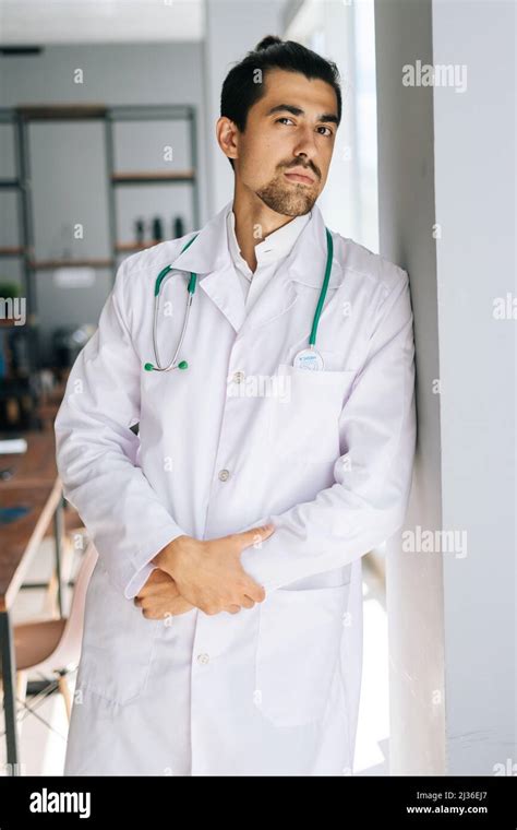 Vertical Portrait Of Serious Male Doctor Wearing White Medical Uniform