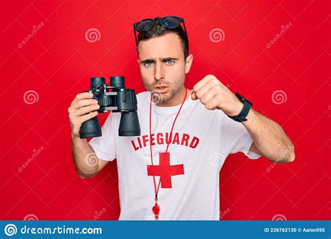 Young Handsome Lifeguard Man Wearing T Shirt With Red Cross And Whistle