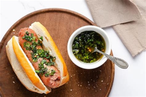 Un Choripan Con Salsa Chimichurri En Una Tabla De Madera Y Una