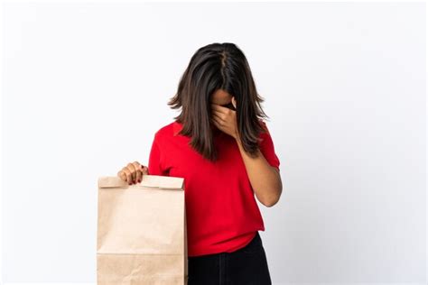 Joven latina sosteniendo una bolsa de compras aislada en blanco con expresión cansada y enferma