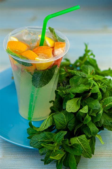 Mojito And Lemonade Summer Cold Drink In A Plastic Glass With A Straw Coctail With Mint Lemon