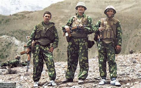 Three Men In Camouflage Uniforms Standing On A Mountain