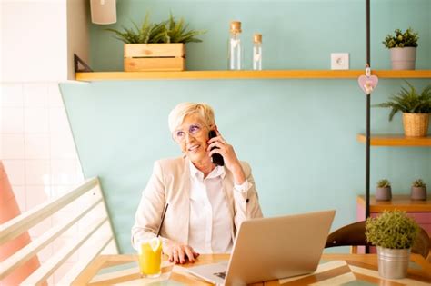 Mulher S Nior Usando Telefone Celular Enquanto Trabalhava No Laptop E