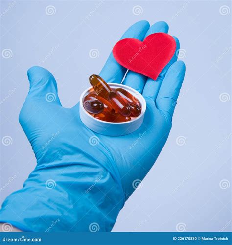 Gloved Doctorâ€™s Hand Holding Red Heart Symbol And Box With Omega