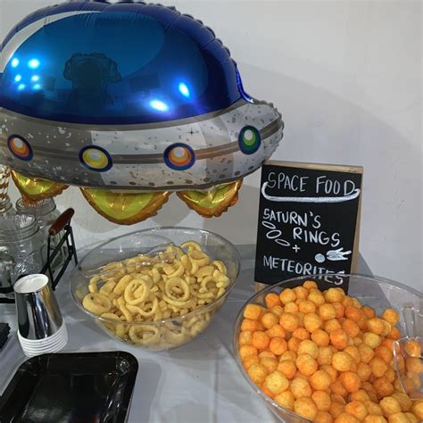 A Table Topped With Lots Of Food Next To A Sign And Balloon Shaped Like