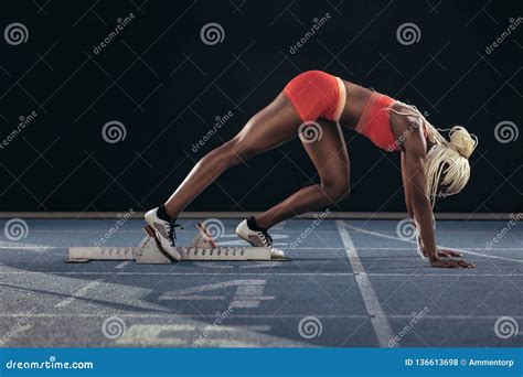 Sprinter Using A Starting Block To Start Her Sprint On A Running Stock