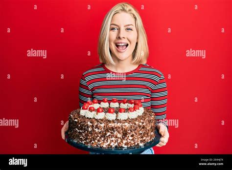 Junge blonde Frau feiert Geburtstag mit großen Schokoladenkuchen lächeln und lachen hart aus