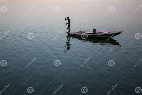 Boatmen On A Boat Glides Through Water On Ganges River Along Shore Of