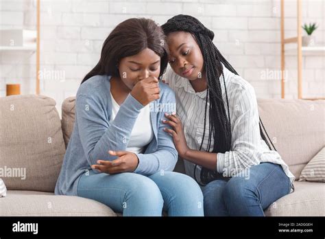 Black Girl Embracing And Comforting Her Upset Friend At Home Stock