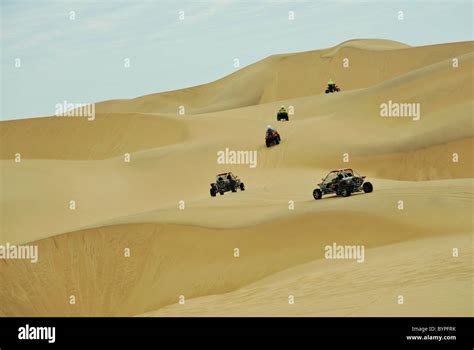 Convoy Of Quad Bikes And Dune Buggies Riding On Yellow Sand Dunes On