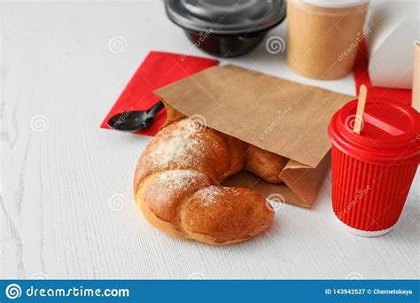 Paper Bag With Pastry And Takeaway Food On Wooden Table Stock Image